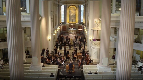 Blick von oben auf ein Orchester in einer Kirche.