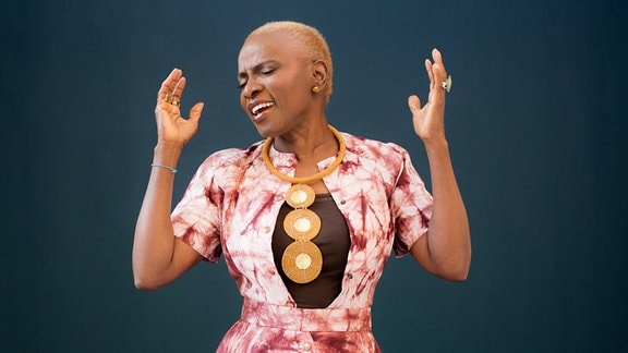 Zu sehen ist die singende Sängerin Angélique Kidjo mit großer goldener Halskette