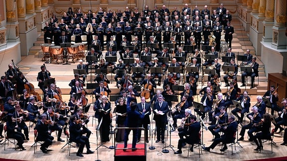 Ein Mann steht auf einem kleinen Podcast vor einem großen Orchester. Es ist die Sächsische Staatskapelle Dresden beim Gedenkkonzert.