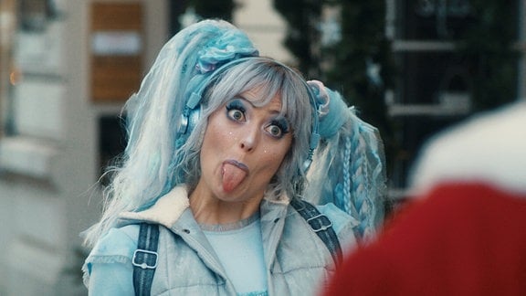 Szene aus dem Kinderfilm "Beutolomäus und die vierte Elfe": Eine Frau in blauem Kostüm streckt die Zunge raus.