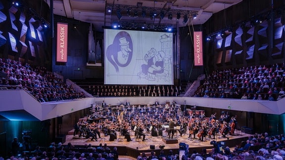 MDR-Sinfonieorchester im Leipziger Gewandhaus beim Festkonzert zum 100. Geburtstag der MDR-Ensembles, darüber eine Leinwand mit einem historischen Stummfilm