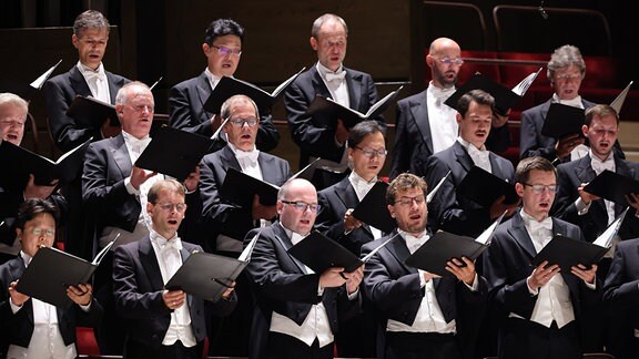 Die Herren des MDR-Rundfunkchors singen mit geöffneten Chormappen in den Händen