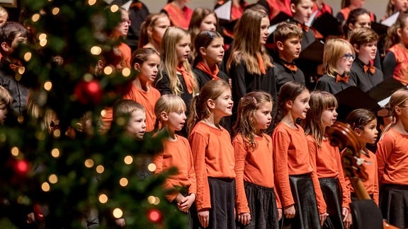 Sängerinnen und Sänger des MDR-Kinderchor beim Weihnachtskonzert neben einem Tannenbaum