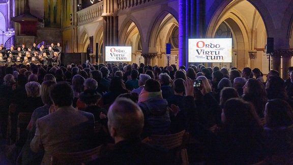 Neben dem Publikum sind Bildschirme aufgebaut bei der Uraufführung von James MacMillans Werk "Ordo Virtutum" im Nachtgesang am 26. Januar 2024 in der Leipziger Peterskirche.
