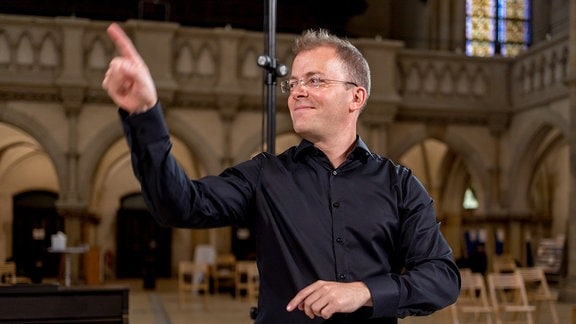 Philipp Ahmann dirigiert Mitglieder des MDR-Rundfunkchors bei einer Produktion in der Leipziger Peterskirche mit einem Werk von Michael Langemann.
