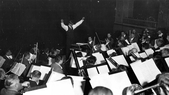 Schwarz-weiß Foto vom Leipziger Sinfonieorchester, vorn dirigiert Howard Hanson