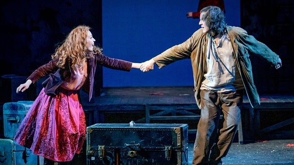 Szene aus einem Theaterstück: Ein Mann zieht eine Frau am Arm mit sich.