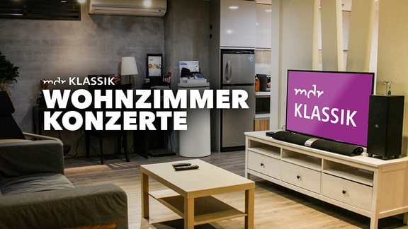 Ein Wohnzimmer im skandinavisch-modernen Stil mit Couch, Couch-Tisch und TV mit großem MDR KLASSIK-Logo. Große Schrift "MDR KLASSIK Wohnzimmer-Konzerte"