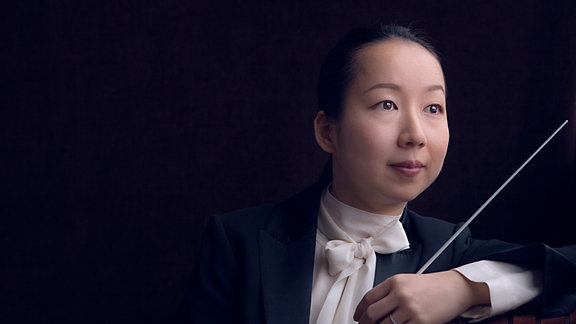 Die Dirigentin Nodoka Okisawa mit einem Taktstock
