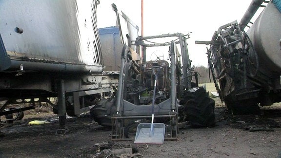 ausgebrannter Traktor zwischen zwei ebenfalls stark beschädigten Landwirtschaftlichen Nutzfahrzeugen