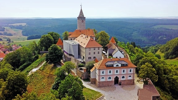 Luftaufnahme einer als Leuchtenburg bekannten Burganlage auf einem grünen Hügel