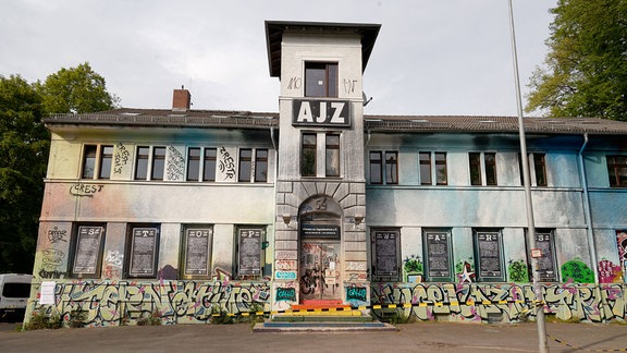 Jugendzentrum AJZ in Chemnitz: ein Gebäude mit weißer Fassade und bunten Graffiti, an der Spitze des Turms der Schriftzug AJZ