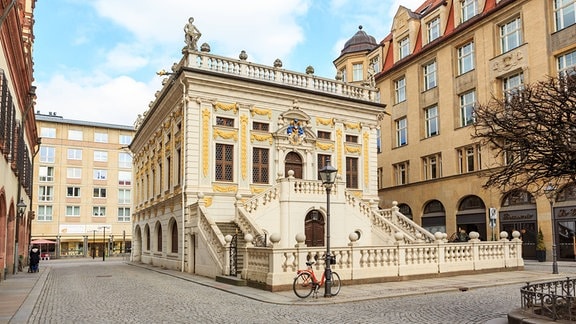 Alte Börse am Naschmarkt in Leipzig: ein historisches Gebäude mit gelb-weißer Fassade, Treppenaufgängen rechts und links und detailreicher Verzierung.