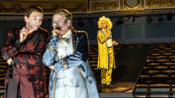 Szene aus dem Stück "Amadeus" über Mozart, zu sehen sind drei Männer in den typischen Kostümen der Rokoko-Zeit