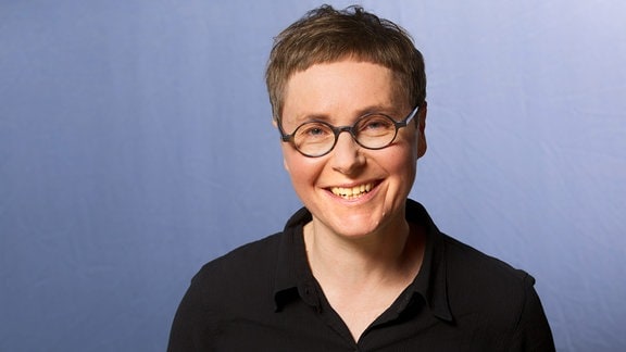Angela Steidele, eine Frau mit kurzen grauen Haaren und Brille, sie trägt ein schwarzes Oberteil