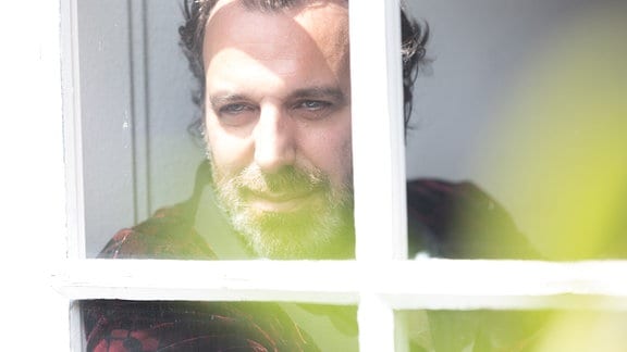 Musiker Chilly Gonzales blickt verträumt aus einem Fenster.