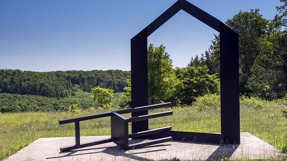 Die Skulptur "Vertreibung", ein Umriss eines Hauses mit einem überdimensionalen umgekippten Stuhl