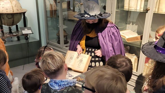Kinder bei einer Halloween-Führung im Museum Bautzen: in der Mitte der Gruppe aus Kindern steht eine als Hexe verkleidete Frau