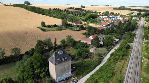 Blick aus der Vogelperspektive auf den Getreidespecher Oßmannstedt: ein graues, bunkerartiges Gebäude, direkt an Bahngleisen