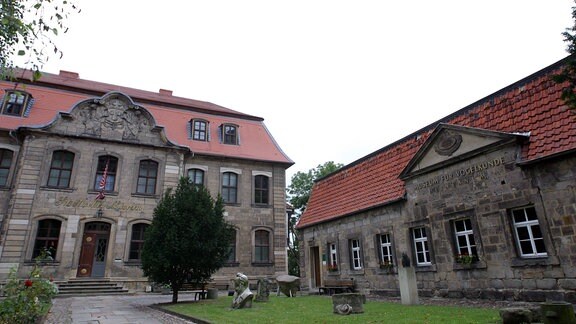 Zwei alte Gebäude des Museums für Vogelkunde sind zu sehen, beide sind aus Stein mit rotem Dach, ein grauer Himmel