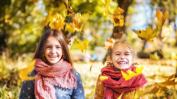 Lachende Mädchen vor herbstlichem Baum.