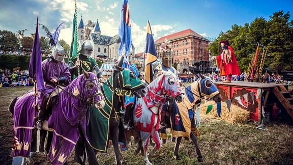 Vier bunte Ritter mit Pferden stehen in einer Reihe bei dem Ritterturnier anlässlich des Kaiser-Otto-Festes in Magdeburg. 