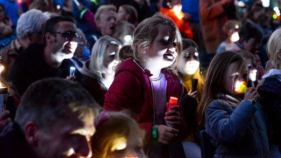 Taschenlampenkonzert: eine Menschenmenge, die von Taschenlampen angestrahlt wird