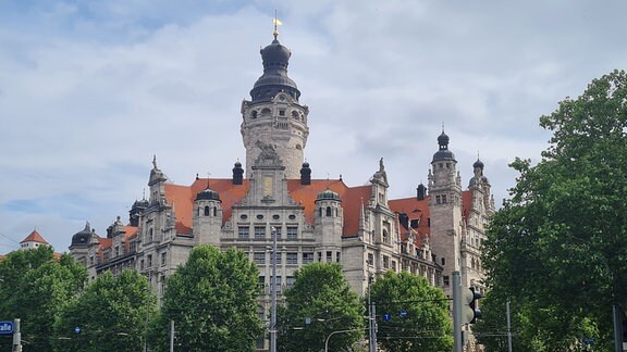 Der Blick auf das neue Rathaus in Leipzig bei gutem Wetter, im Vordergrund die Straße mit Autos und Fahrrädern 