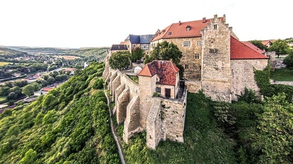 Schloss Neuenburg, eine historische Burg auf einem Berg umgeben von Grün.