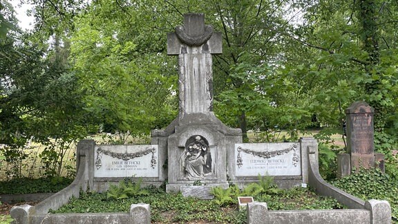 Das Familiengrab von Ludwig Bethcke auf dem Nordfriedhof in Halle (Saale): eine niedrige graue Mauer umringt eine begrünte Fläche, in der Mitte ein Steinkreuz
