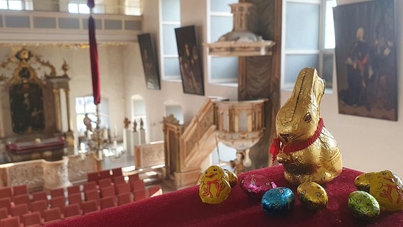 In einer alten Kirche sind Goldhase und Schoko-Eier ausgestellt.
