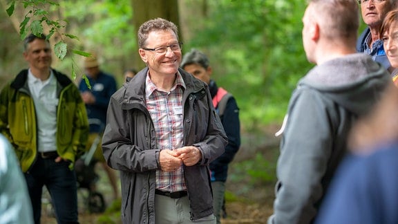 Der Nationalparkführer Jürgen Dawo steht vor einer Gruppe von Menschen im Wald.
