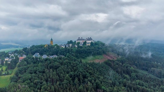 Jagdschloss Augustusburg auf einem bewaldeten Hügel in Nebel und Regen 
