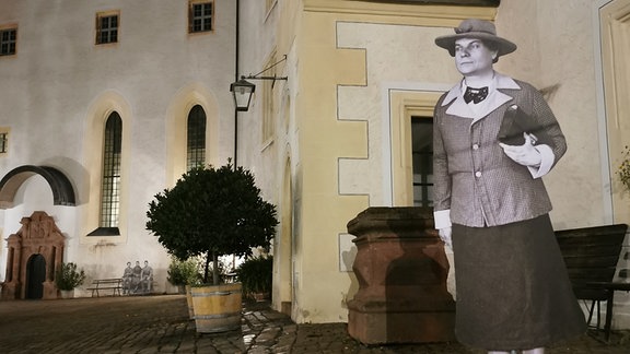 Die Pappfigur einer Frau steht im nächtlichen Hof des Schloss Colditz.