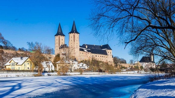 Schloss Rochlitz im Winter, im Vordergrund Schnee und eine Wasserfläche