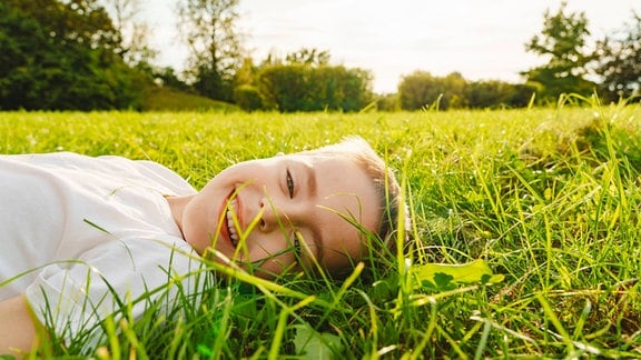 Ein Junge liegt auf einer Wiese und lacht