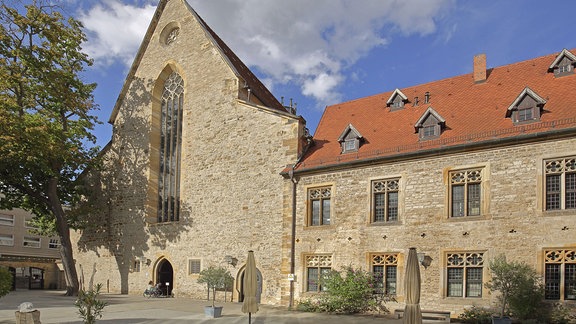 Kloster St. Peter und Paul mit heller Fassade und rotem Dach vor blauem Himmel