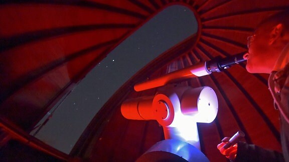 Mann schaut durch ein Teleskop in der Sternwarte Urania Jena