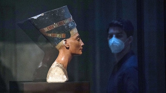 Ein Mann mit Gesichtsmaske geht im Neuen Museum an der Büste der Nofretete vorbei. 