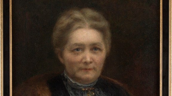 Porträt-Gemälde in Öl von Alwine Arnold: Eine Frau in dunklem Mantel blickt die Betrachtenden an.