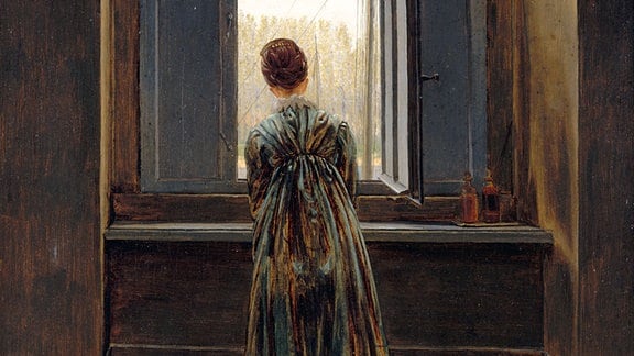 Ein Gemälde von Caspar David Friedrich , eine Frau steht am Fenster, wendet dem Betrachter den Rücken zu und versperrt die Sicht nach außen