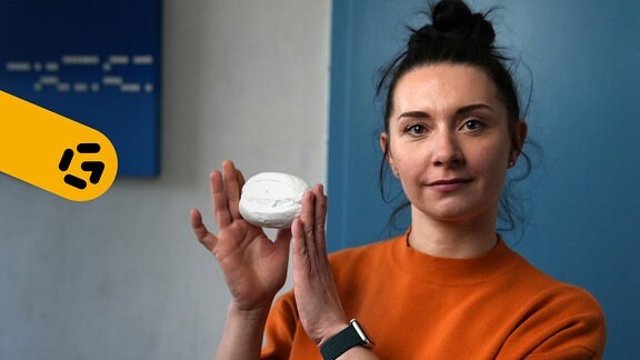 Ein Porträt der Künstlerin Cosima Göpfert, in der Hand hält sie ein weißes Brötchen aus Porzellan.