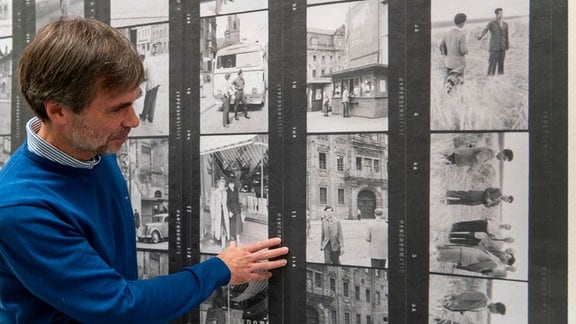 Zu sehen ist der Kurator Daniel Blochwitz wie er auf eine Fotografie in der Ausstellung zeigt.