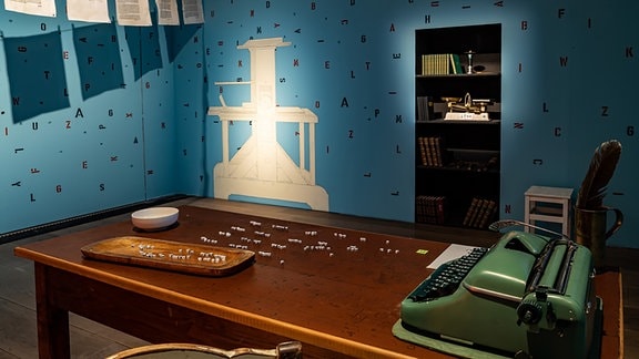 Ein Schreibtisch mit einer Schreibmaschine und kleinen Buchstabenwürfeln