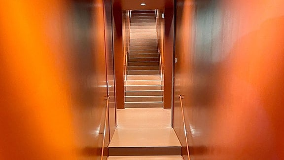 Eine lange, schmale, rote Treppe über mehrere Etagen.