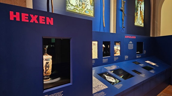 Blick in eine Ausstellung, bei der verschiedene beleuchtete Objekte zu sehen sind.