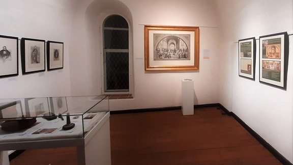 Blick in einen Ausstellungsraum in Havelberg mit Vitrinen und Bildern an der Wand.