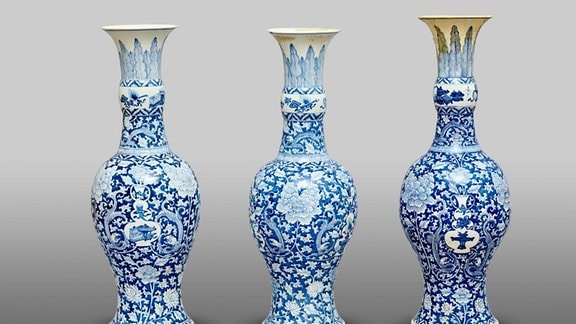 Drei blau angemalte Kangxi Vasen stehen nebeneinander vor neutralem Hintergrund.