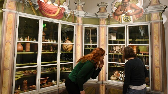 Zwei Frauen schauen in eine Vitrine in der Ausstellungsobjekte liegen