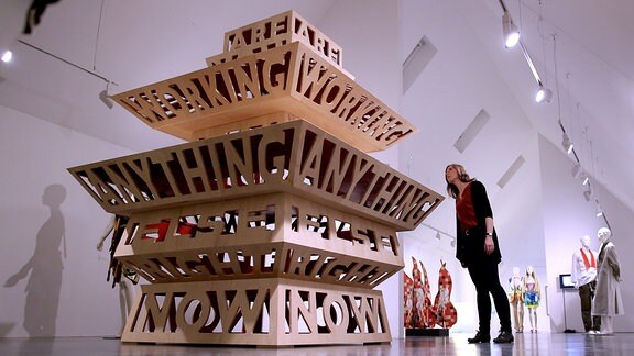 Eine Frau betrachtet das Werk "Tempel" des deutschen Künstlers Michael Hofstetter, das die Form eines Tempels hat, hedoch mit Wänden, die aus Buchstaben Wörter formen